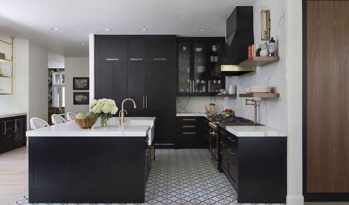 contemporary kitchen design with black cabinets, white walls, and oversized brass bar pulls