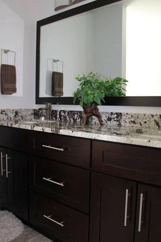 Dark theme Bathroom design with brown vanity with quartz countertops, and large mirror