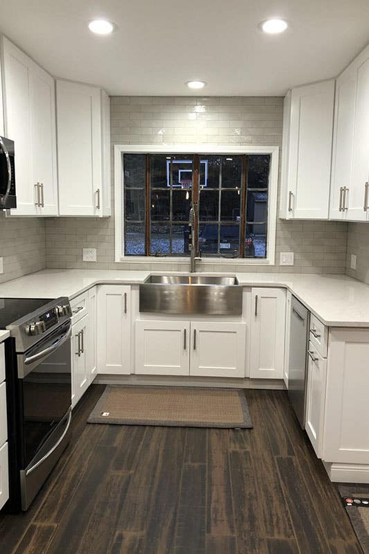 U Shape kitchen design with white cabinets, subway tiles backsplash, Farmhouse sink and one large window