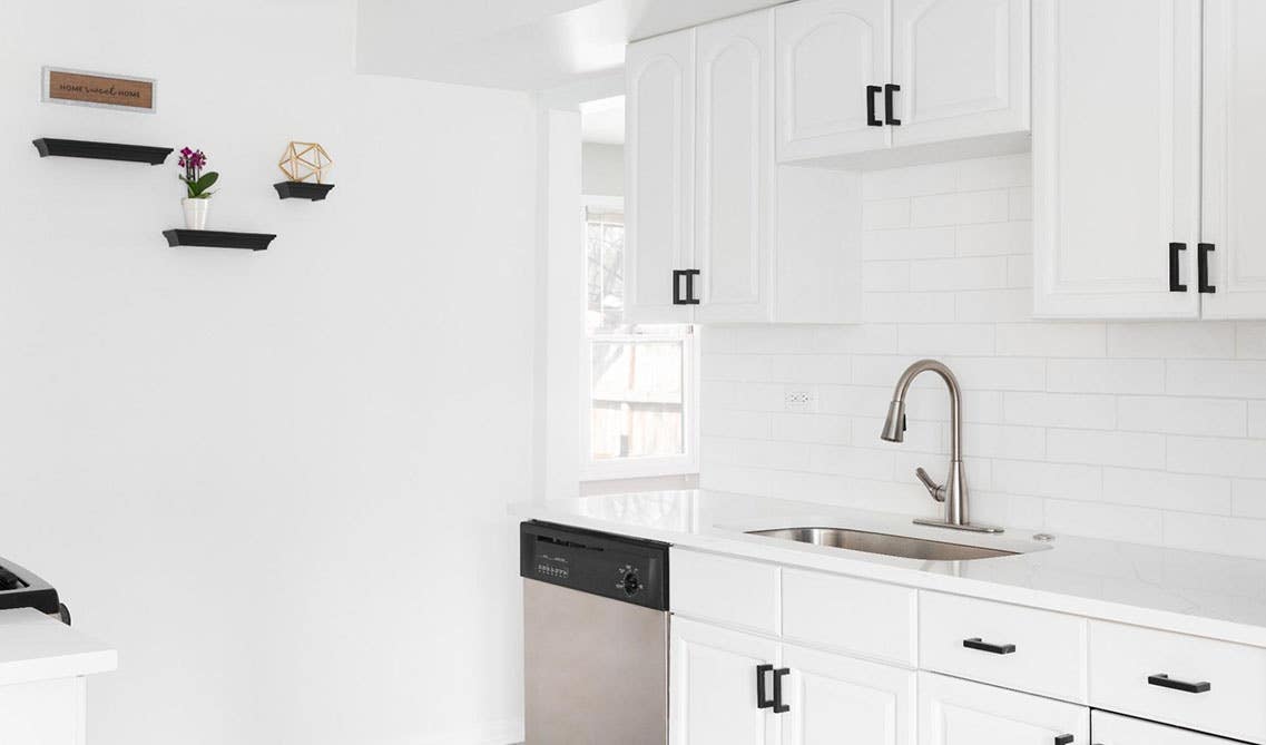 white and black kitchen with shaker cabinets, floating shelves and stainless steel appliances