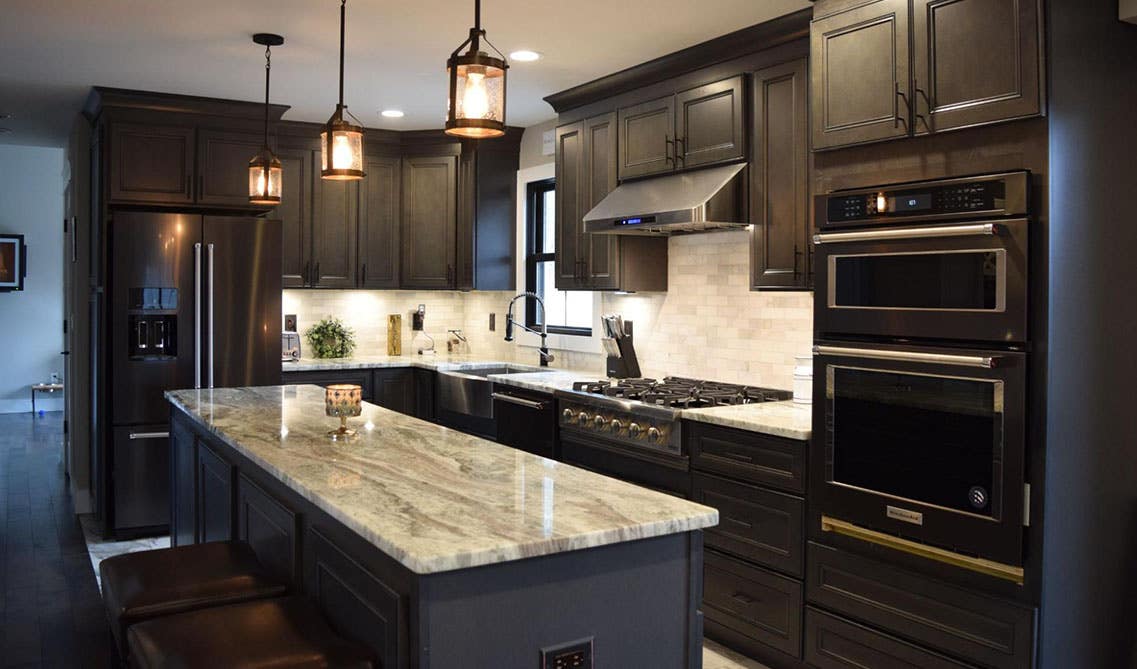 Kitchen with York Driftwood Grey cabinets, ductless range hood, marble countertop and small island 