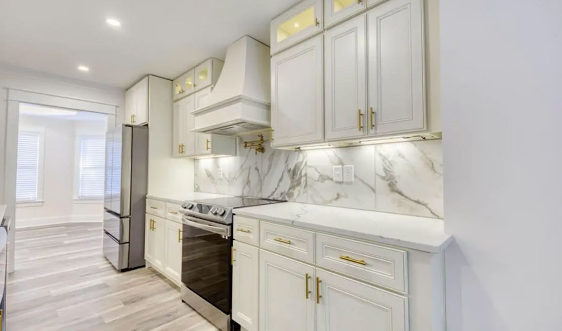 Durable Solid Slab Backsplash paired with cream kitchen cabinets and SPC Flooring 