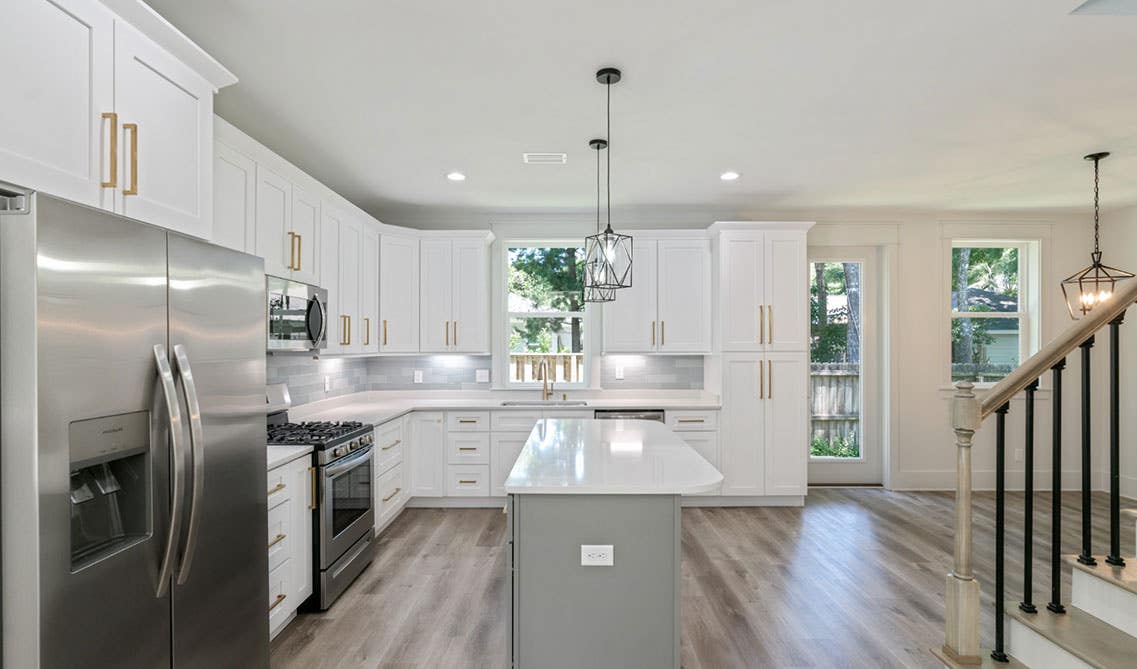 Open kitchen design with white cabinets, gold hardware and stainless steel appliances 