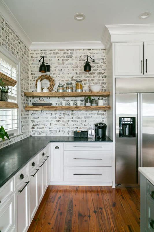 Painted Brick Backsplash with Floating Shelves, black countertop and bright white cabinets