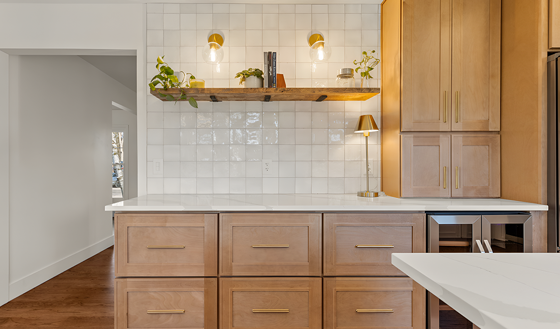 Natural wood cabinets paired with white subway tiles, quartz countertop, and floating shelve