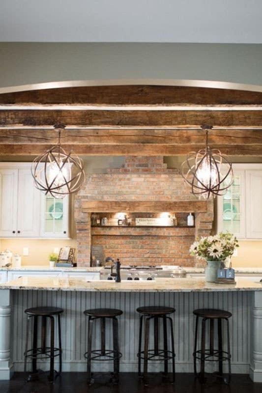 Europeans rustic kitchen with circular pendant lights, large rustic kitchen island and wood beams