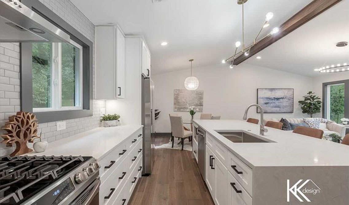 Kitchen with white shaker cabinets with black pulls, stainless steel appliances and wooden floorings