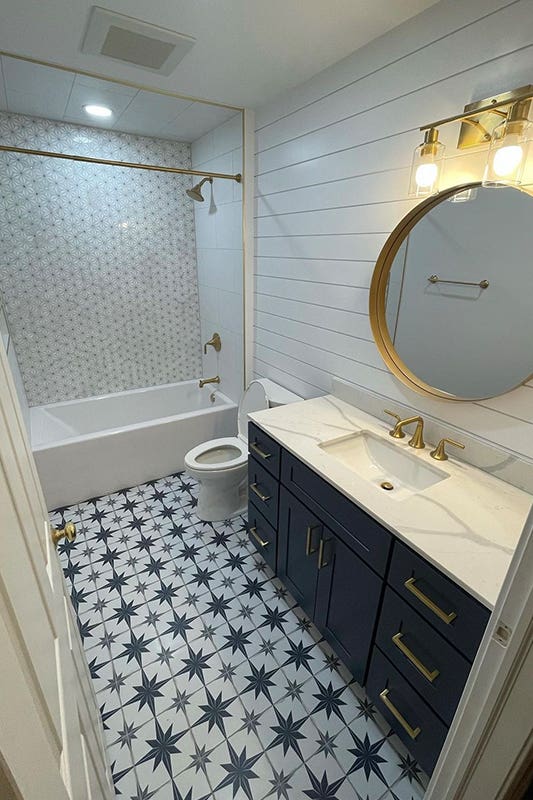 bathroom design with Mosaic tile backsplashes, decorative floor patterns, and navy blue vanity 