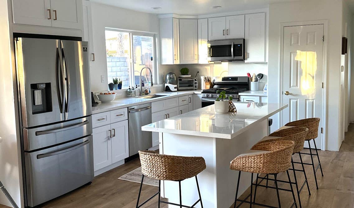 White kitchen with stainless steel appliances and wood flooring