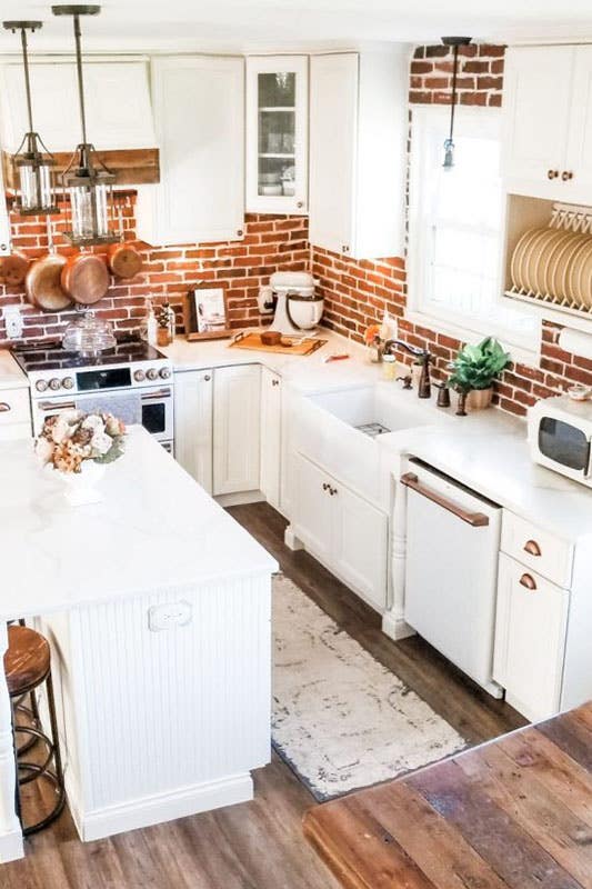 Farmhouse kitchen with white cabinets and brick style backsplash