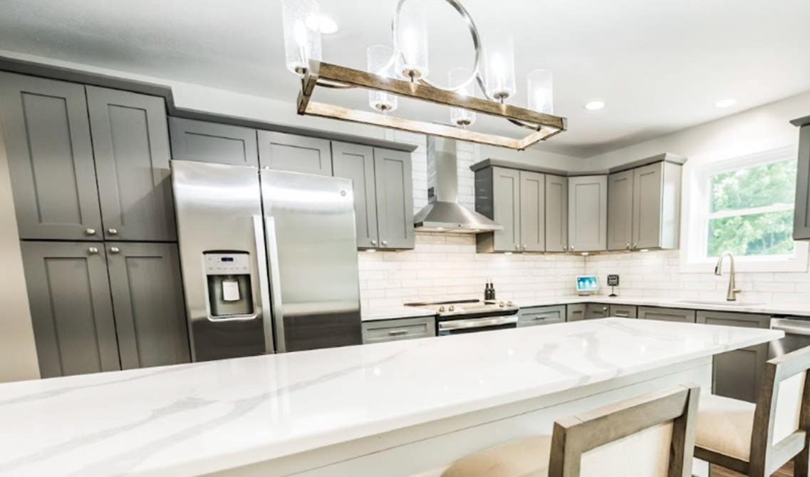 kitchen with dual gray and white cabinets, small island, marble countertop and Farmhouse Lighting