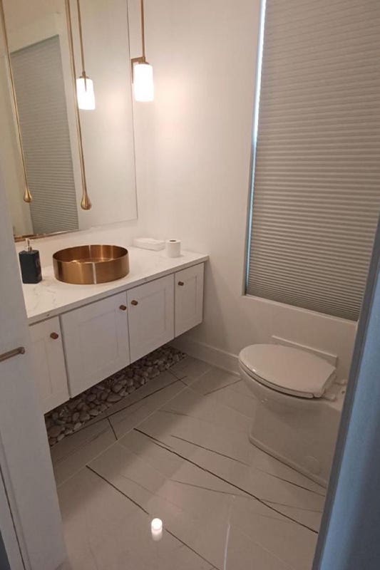 white bathroom paired with floating vanity, brass sink, and marble flooring 
