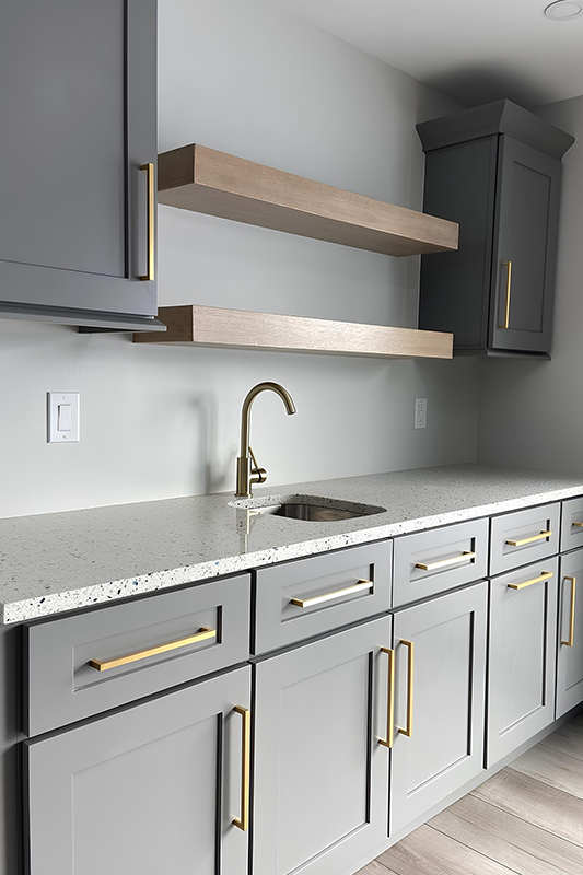 Small kitchen design with gray cabinets, gold pulls and Wooden floating shelves