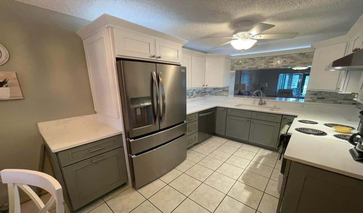 Forest green kitchen cabinets with quartz countertops and stainless steel appliances 