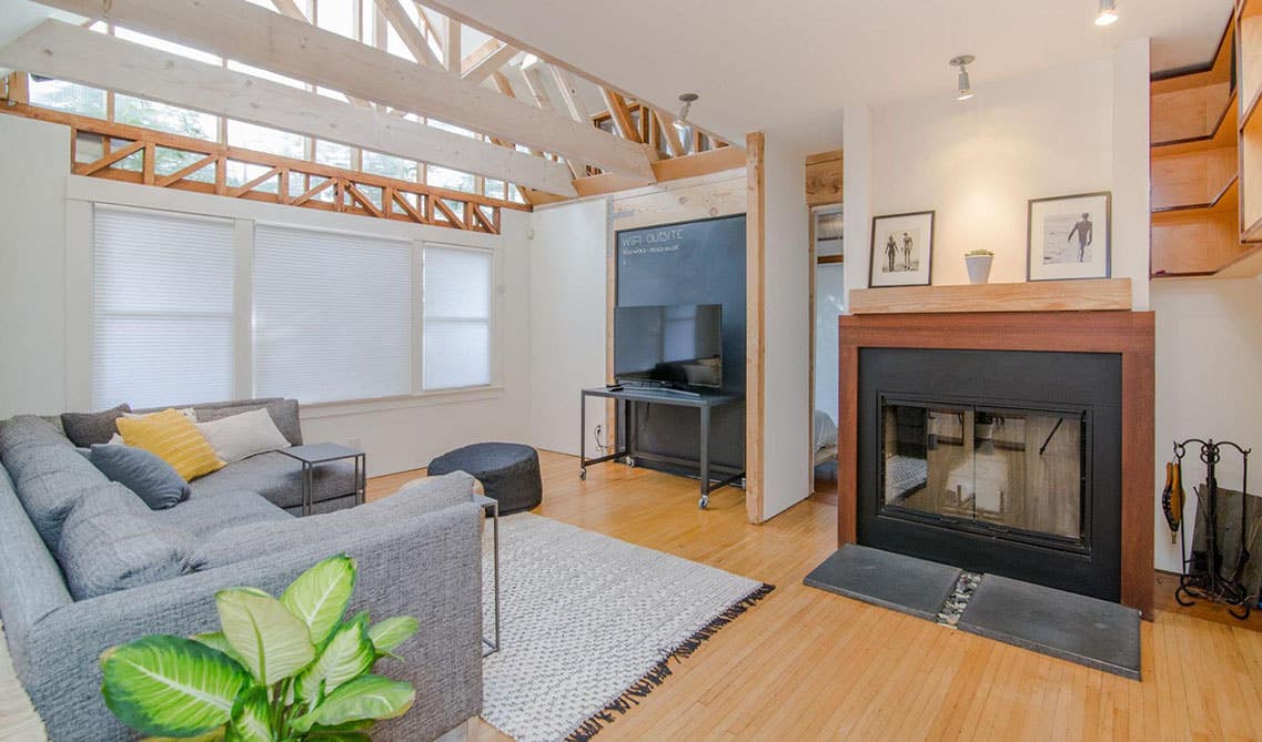 welcoming living room with electric fireplace, gallery wall, gray sofa, wooden flooring and Coastal Rug