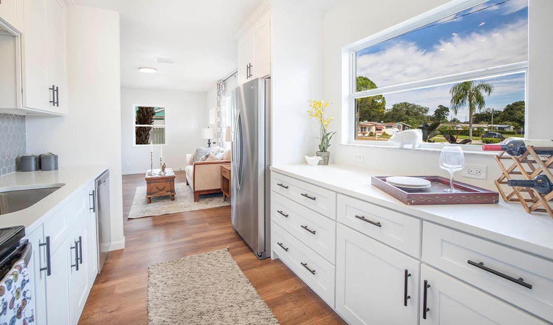 Galley Kitchen layout with white cabinets and black hardware, large window 