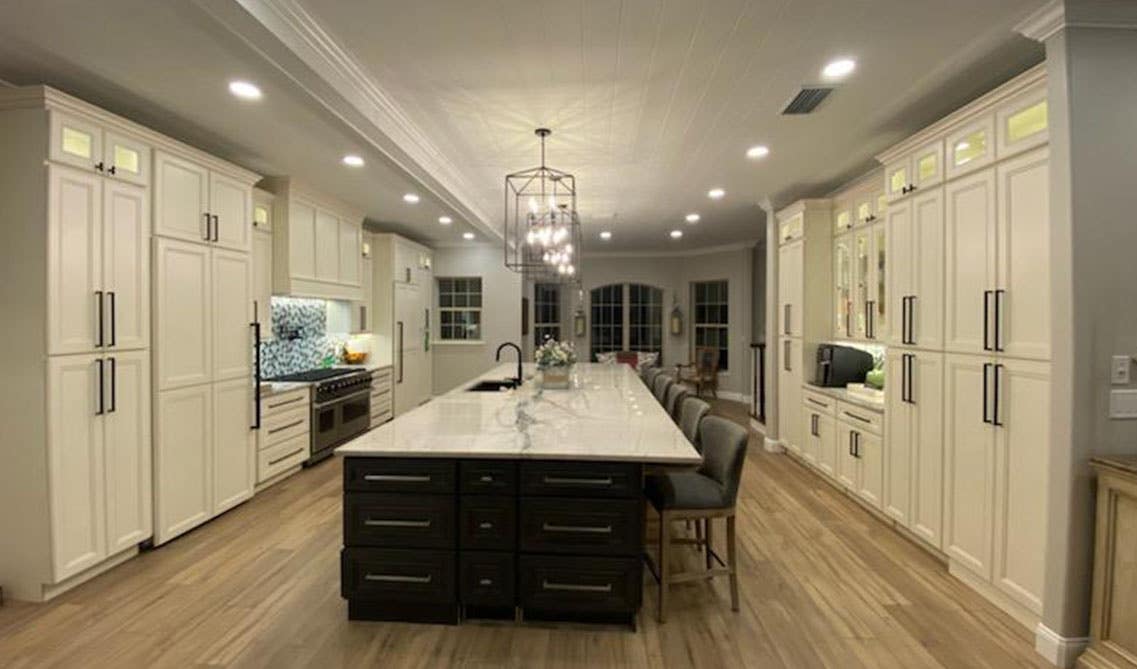 Galley kitchen layout with large island with dark brown cabinets and Chandelier Hanging Pendant Ceiling Lights 