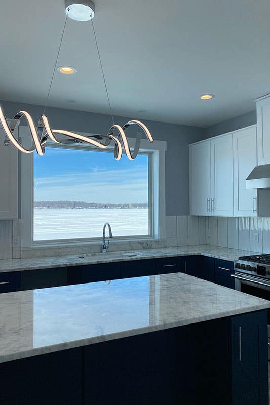 kitchen with white cabinets, small island, marble countertop and Geometric Fixtures