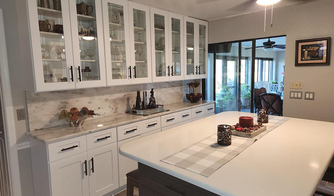 White cabinets with glass door with large island, white countertop, 