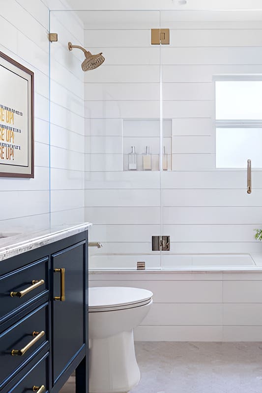 Bathroom design with glass partitions to shower, blue vanity and gold hardware
