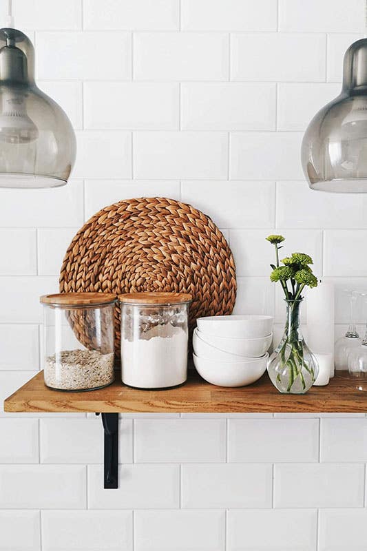 Glass container above wooden shelves, pendent lights and subway tiles 