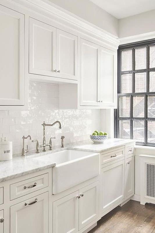 Glossy Brick Backsplash with white shaker cabinets and farmhouse sink