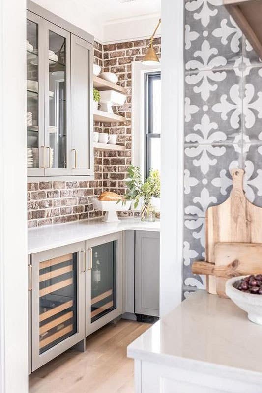 Red Brick Backsplash with gray shaker cabinets and marble countertops