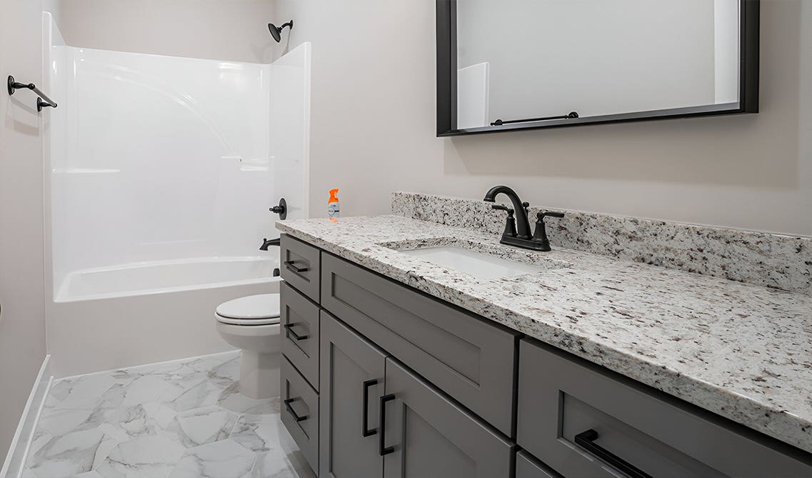 Gray bathroom vanity with black pulls and quartz countertop