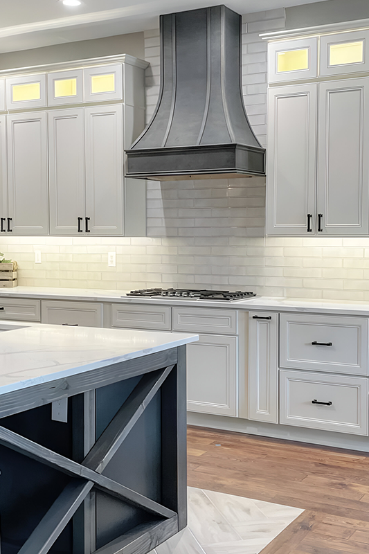 Gray wood hood paired with white shaker cabinets