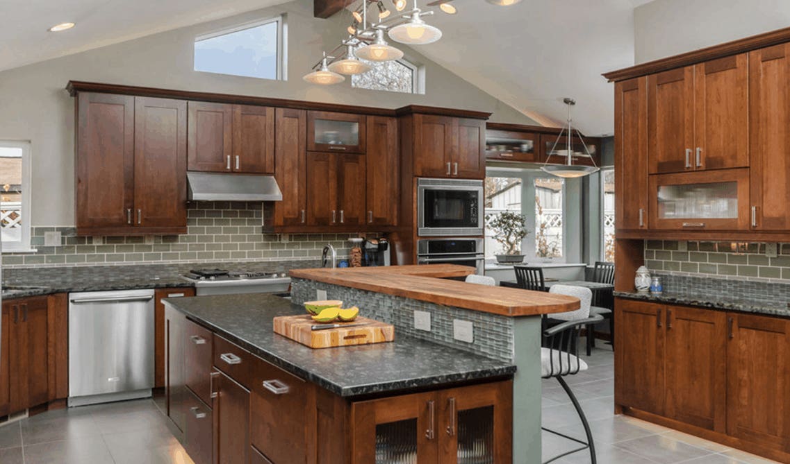  cherry kitchen cabinets with Green tile backsplashes and marble countertop 