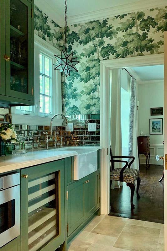 Kitchen features green cabinets, white countertops and Green Botanical Wallpaper and 