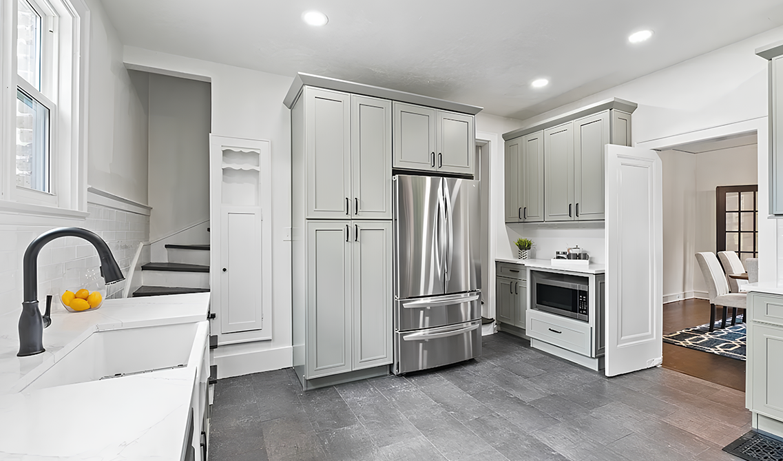 White kitchen features sage green cabinets and stainless steel appliances 
