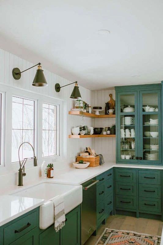 farmhouse kitchen features green cabinets, white wall, and ceramic kitchen sink