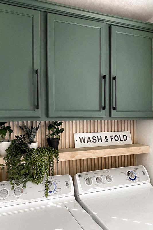 Laundry room with green storage cabinet and wooden shelving, washer and dryer 