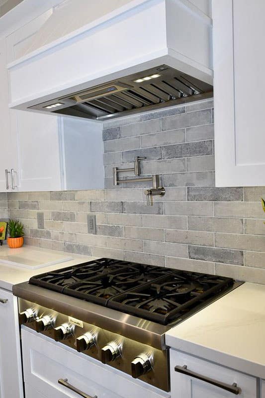 Grey Brick Backsplash with white shaker cabinets and Stainless Steel Appliances