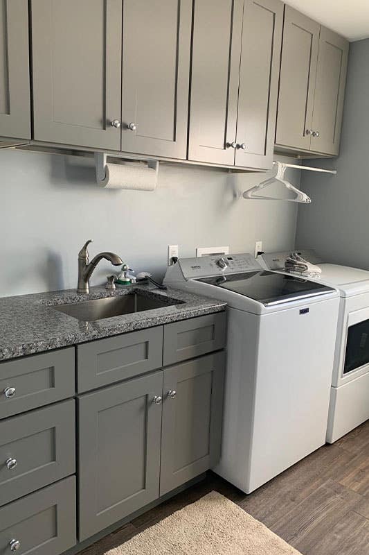 Small laundry room with grey shaker cabinets, washer and dryer, and spc flooring 