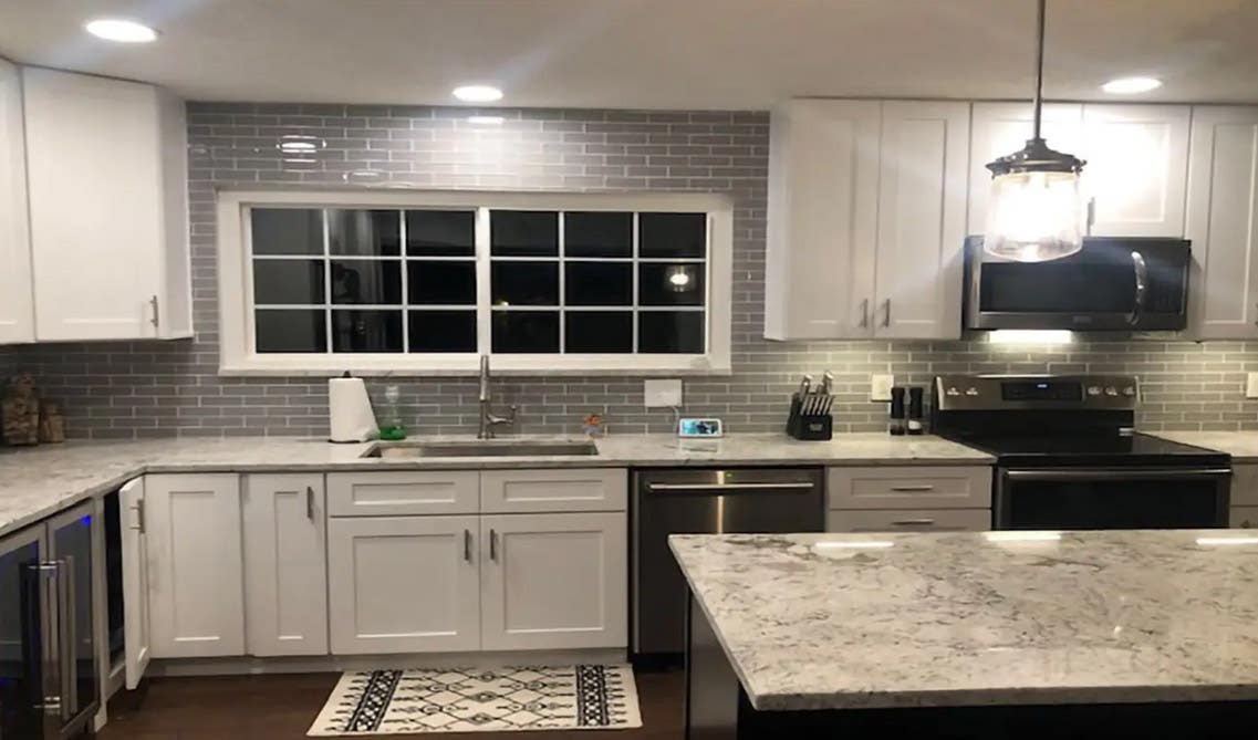 White kitchen cabinets with gray subway tiles and stainless steel appliances 