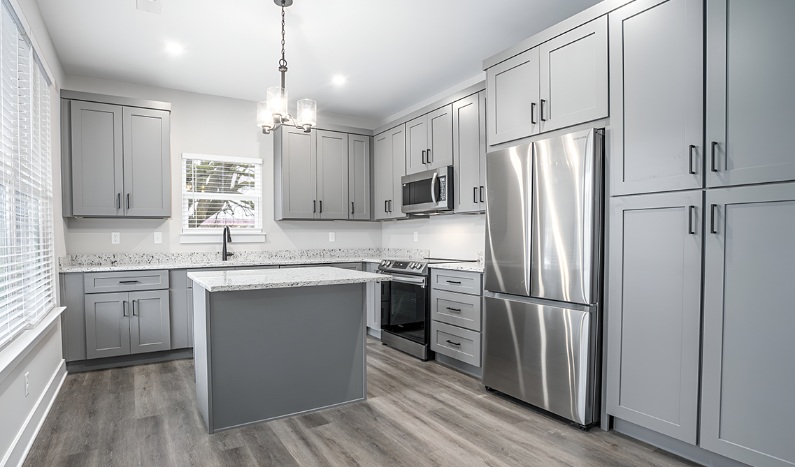 Grey Shaker elite kitchen cabinets paired with concrete countertop, stainless steel appliances and laminate flooring 