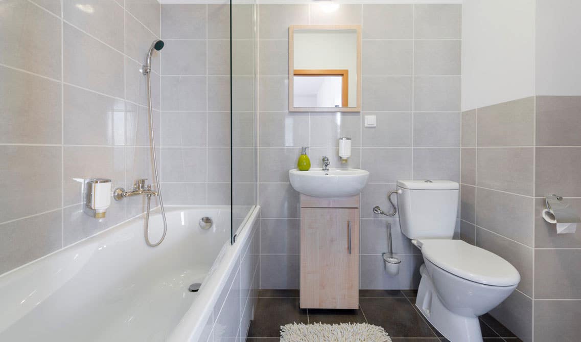 Bathroom design features halfway tiled wall, single vanity with ceramic sink, toilet sheet and bathtub