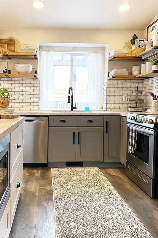 Kitchen with grey shaker cabinets,matt black hardware, marble countertops, floating shelves and wooden flooring