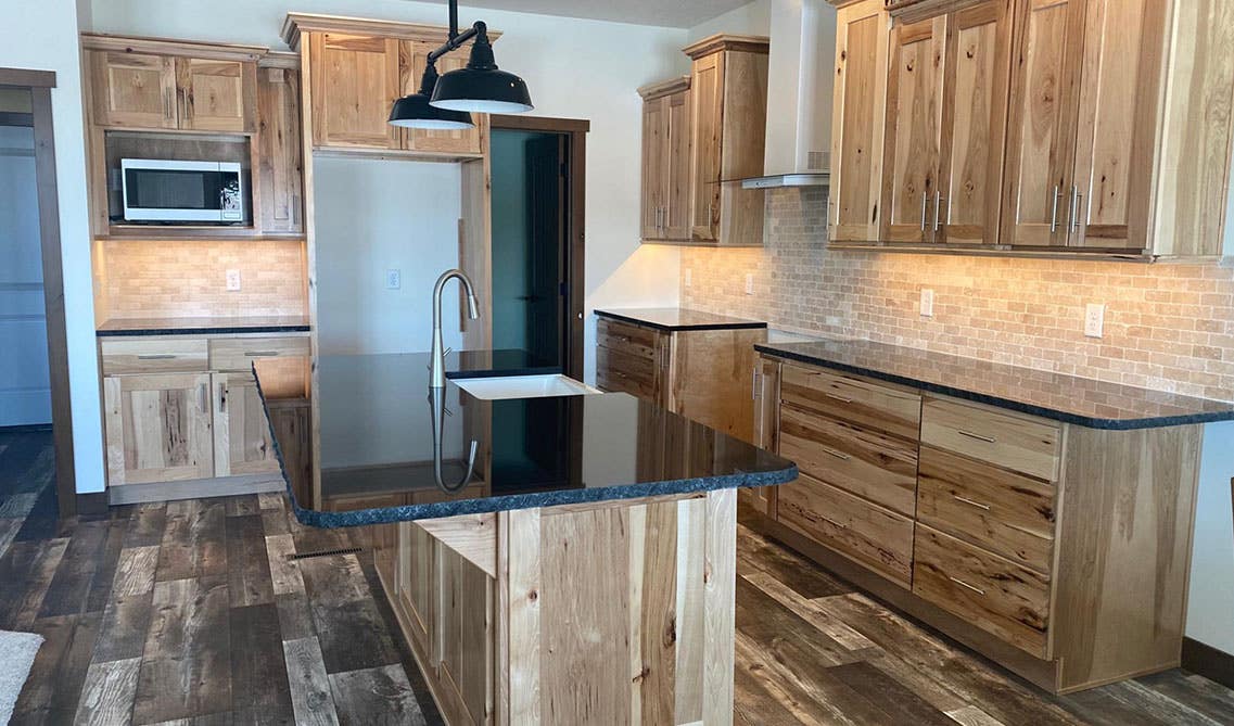 Natural wood cabinets paired with white countertop and hardwood flooring