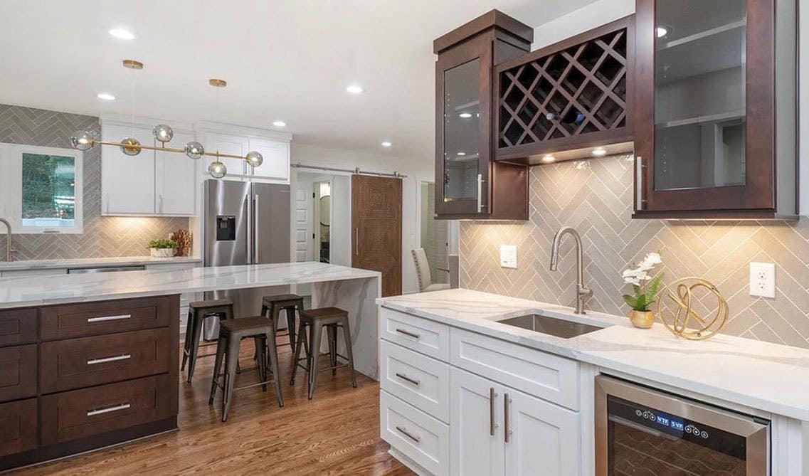 Kitchen design with white and brown cabinets with glass door and Herringbone Tile backsplash 