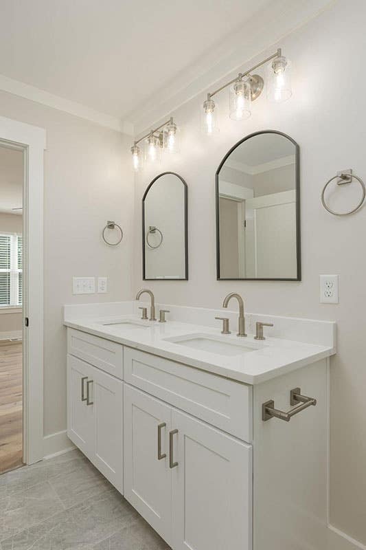 Modern bathroom with white cabinets, silver hardware and lighting fixtures 