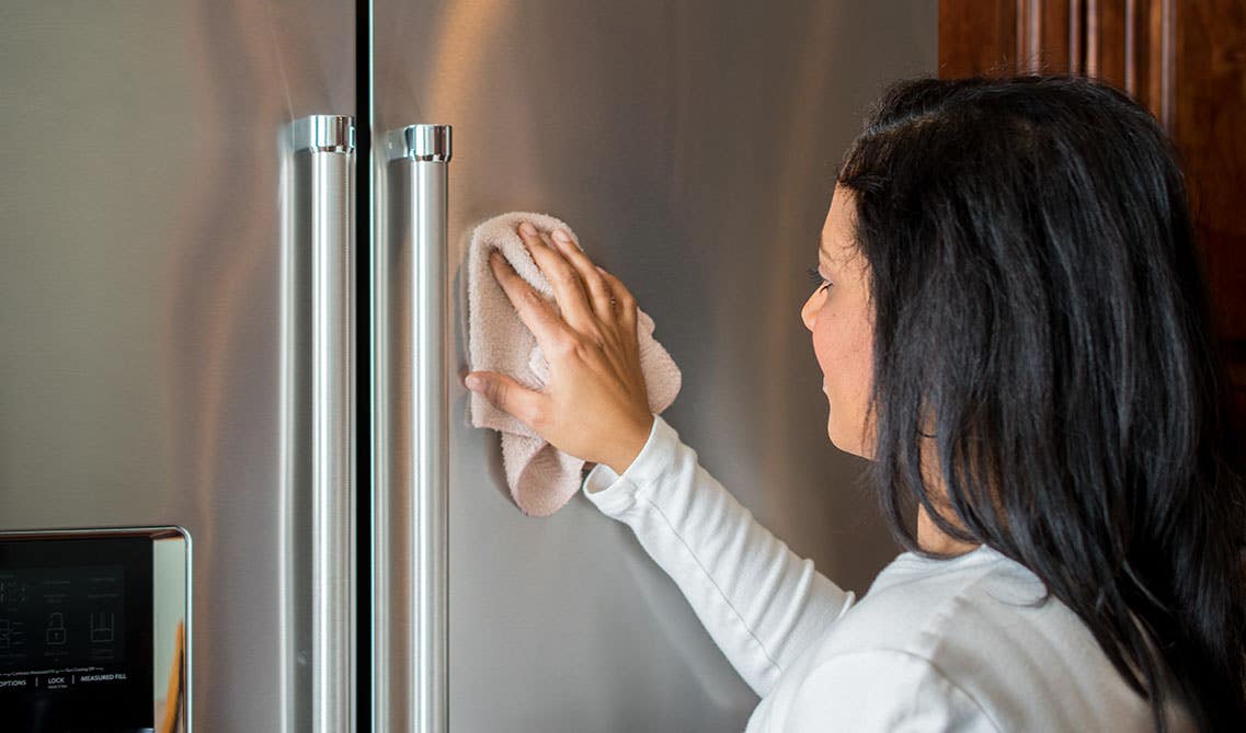 lady cleaning stainless steel refrigerator with Microfiber cloth