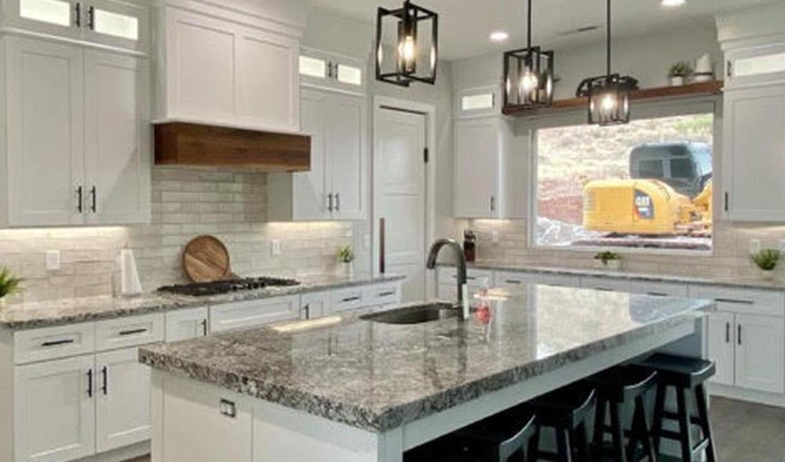 kitchen with white shaker cabinets and large island with undermount sink