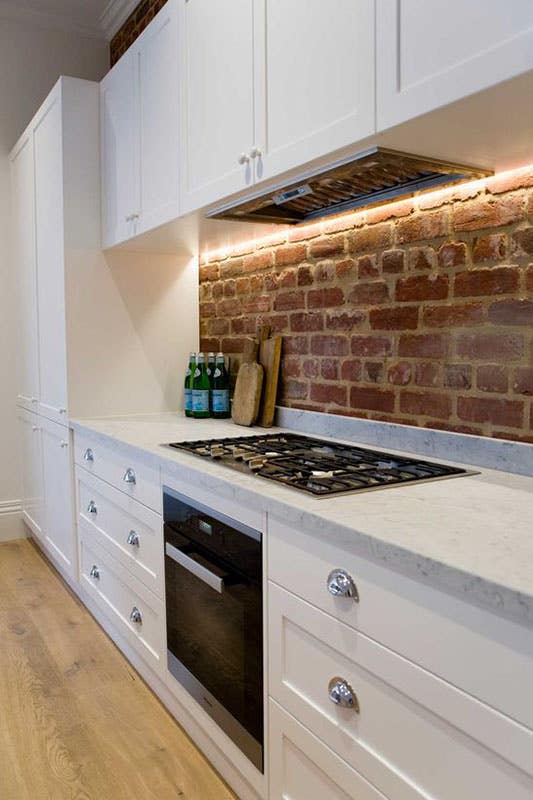 Industrial Brick Backsplash with Marble countertop and white cabinets