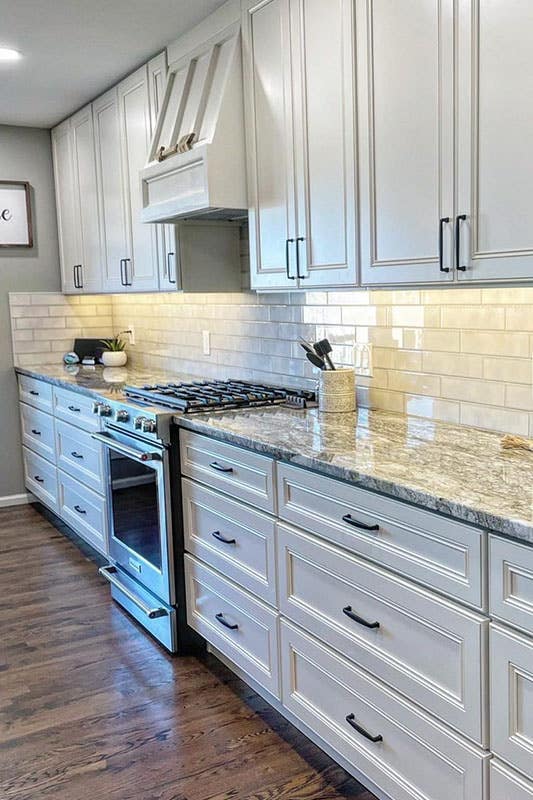 Single wall kitchen with white cabinets and black hardware, marble countertop, 