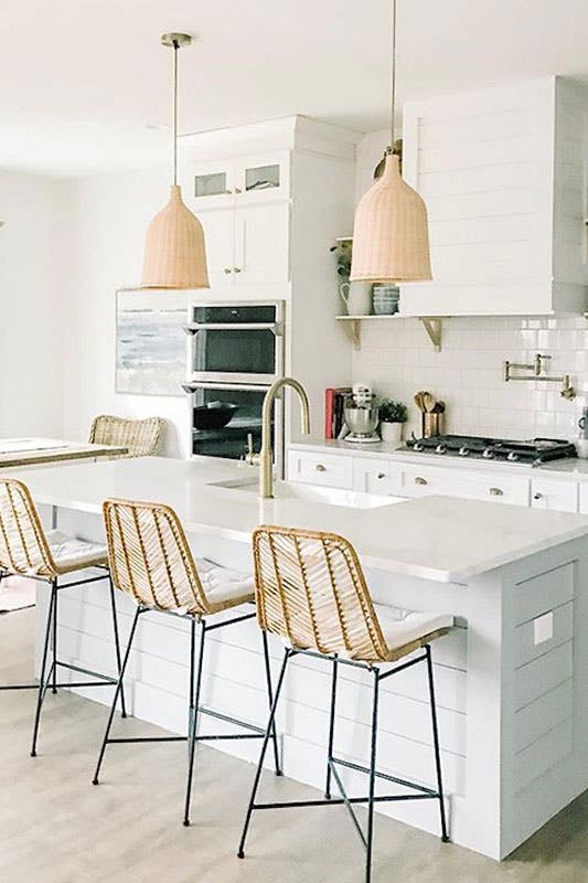 Warm white kitchen with natural wooden chair, white cabinets and white subway backsplash tiles