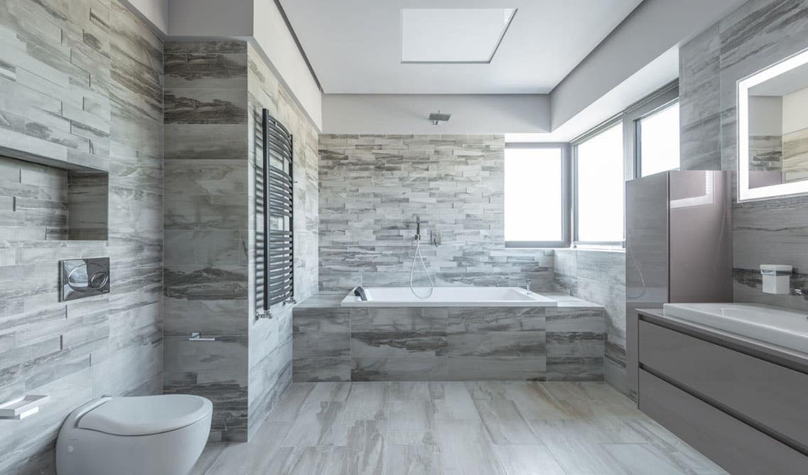 Bathroom design features tile on floor and wall, wall mounted vanity and bathtub