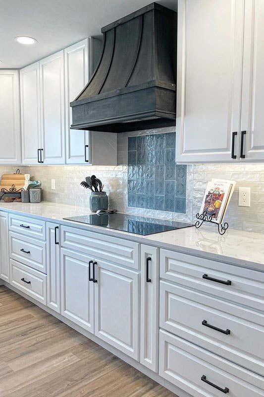 Modern kitchen with Key Largo White Cabinets and black range hood